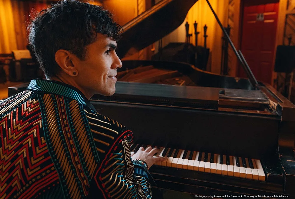 Ryan Marquez performing at a grand piano wearing a colorful patterned jacket.