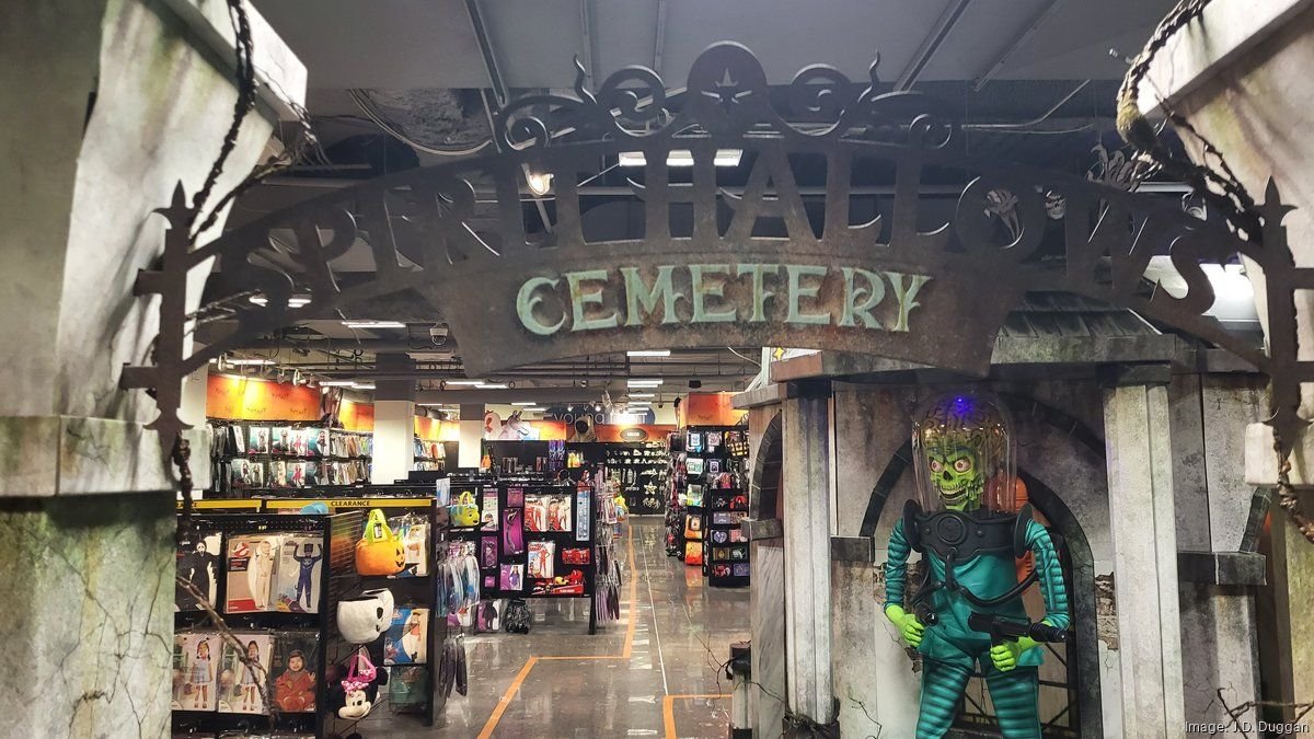 Inside a Spirit Halloween store in St. Louis featuring a haunted cemetery entrance, costumes, and animatronic Martian display.