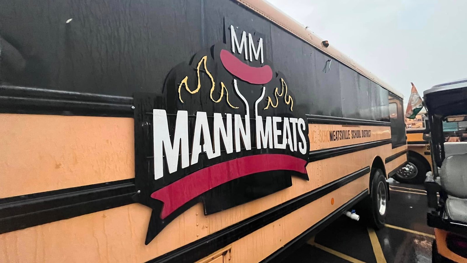 Mann Meats Florissant food truck parked in Missouri, featuring the original black and yellow school bus design with the Mann Meats BBQ logo.