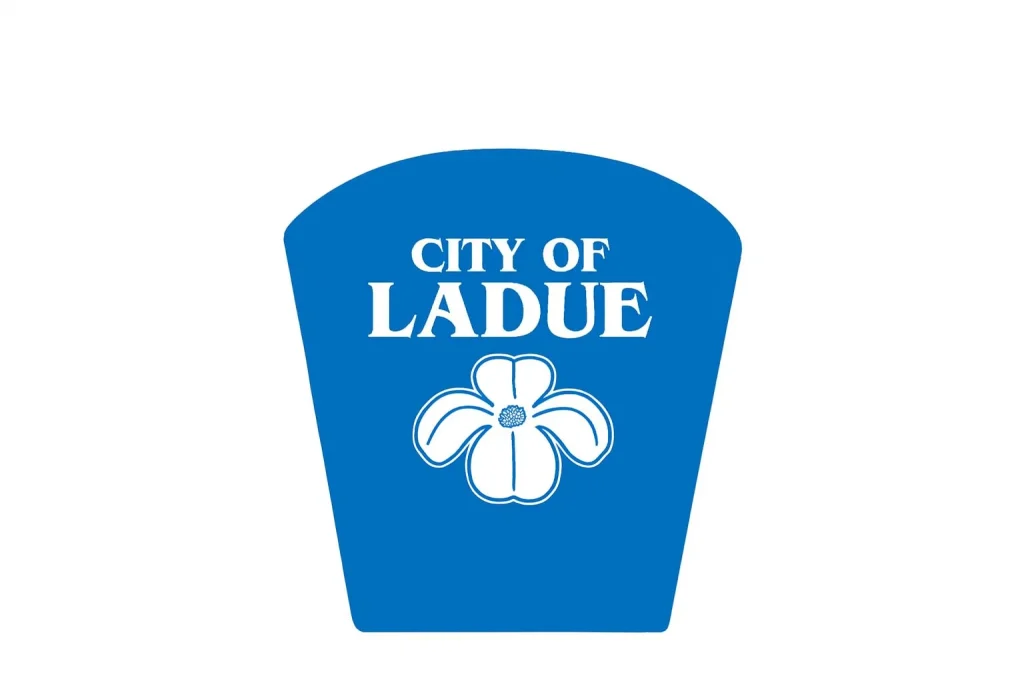 City of Ladue blue logo featuring a white flower, representing the community near homes for sale in Ladue MO.